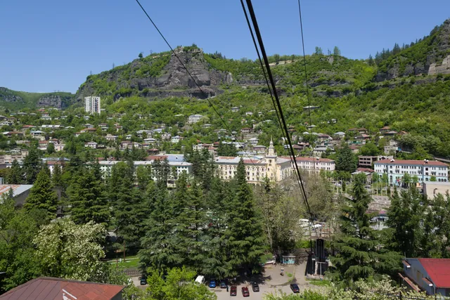 Panoramic view of Chiatura from the cable car — Stalinist building with spire and mountain slopes covered in houses