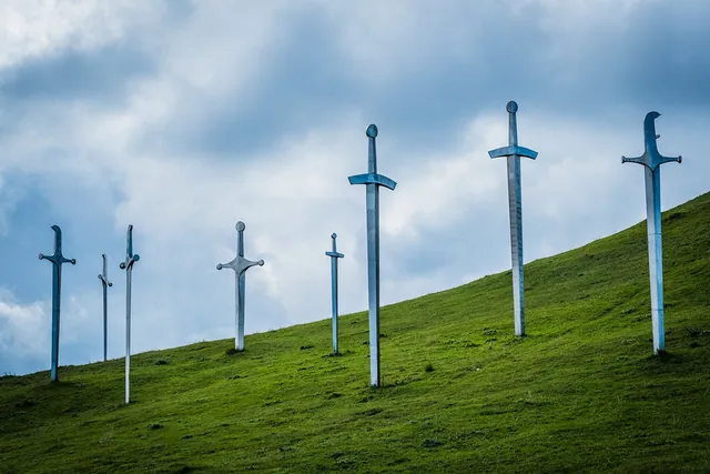 Stone swords of the Didgori Memorial rising from a green hillside under a dramatic cloudy sky, Georgia