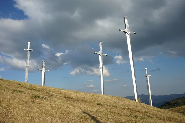Stone swords of the Didgori Memorial on a dry hillside with Georgian mountain landscape in the background