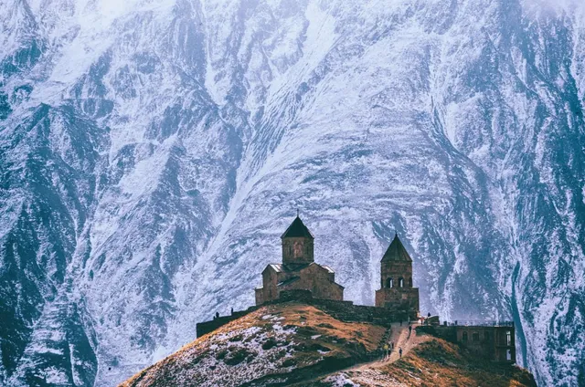 Gergeti Trinity Church on a hill surrounded by snow-covered mountain slopes in winter, Stepantsminda