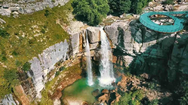 Aerial view of Kinchha Waterfall — lower cascade, turquoise pool, and circular viewing platform