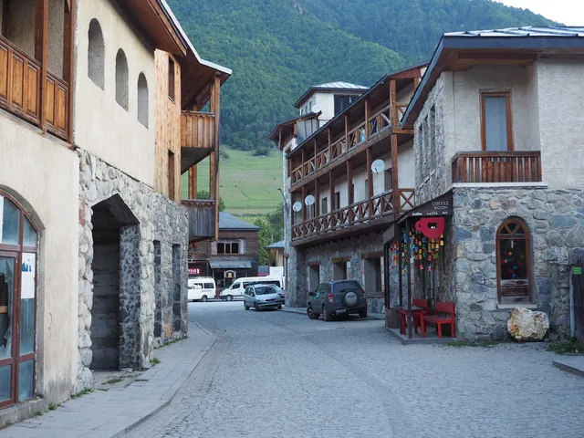 Cobbled street in central Mestia: stone walls, wooden balconies and a mountain behind the roofs