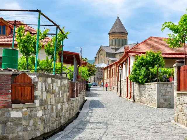 Cobblestone street in Mtskheta old town with Svetitskhoveli Cathedral dome visible at the end