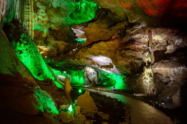 Green-and-orange lighting on the stalagmites along the Prometheus Cave route