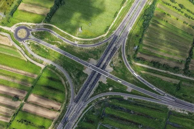 Aerial view of a modern interchange on the E60 highway among green fields