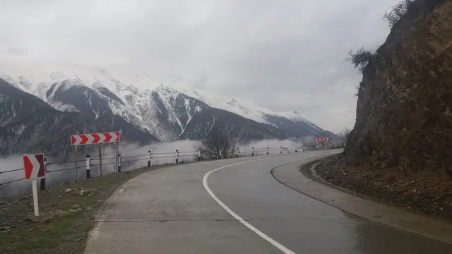 Switchbacks above the clouds with the snow-covered peaks of the Caucasus