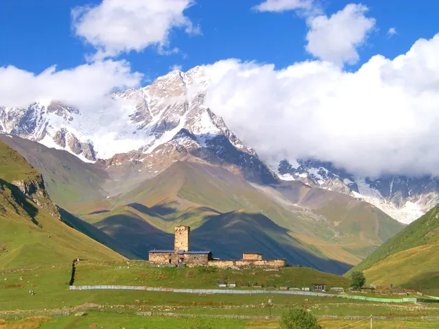 Lamaria church and a Svan tower against snowy peaks