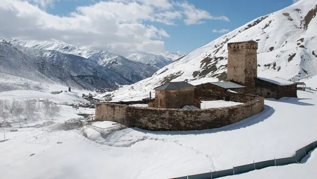 Ushguli in winter: Lamaria church and Svan tower covered in deep snow, Svaneti Georgia